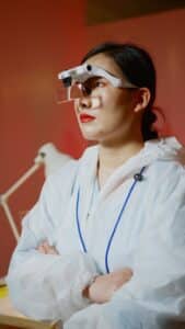 young woman standing in white lab coat looking afar